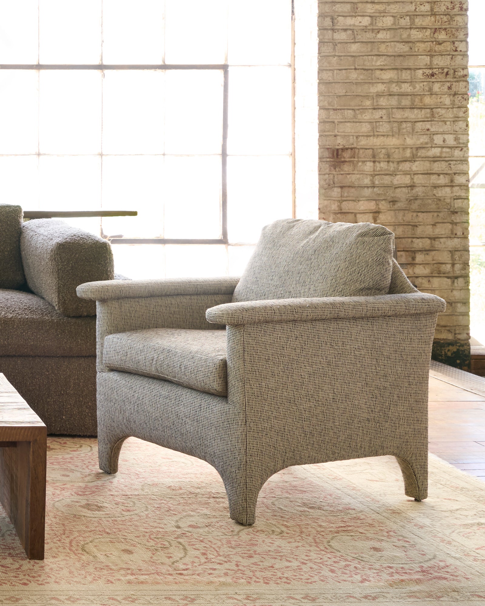  Beige armchair in a living room with a couch and coffee table. Photographed in Ferrara Charcoal. 