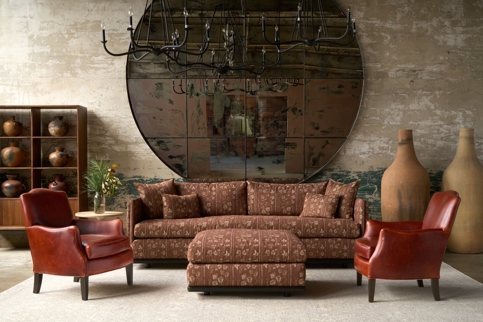  Living room with patterned sofa, red chairs, and large mirror on the wall. Photographed in Foret Rust. 
