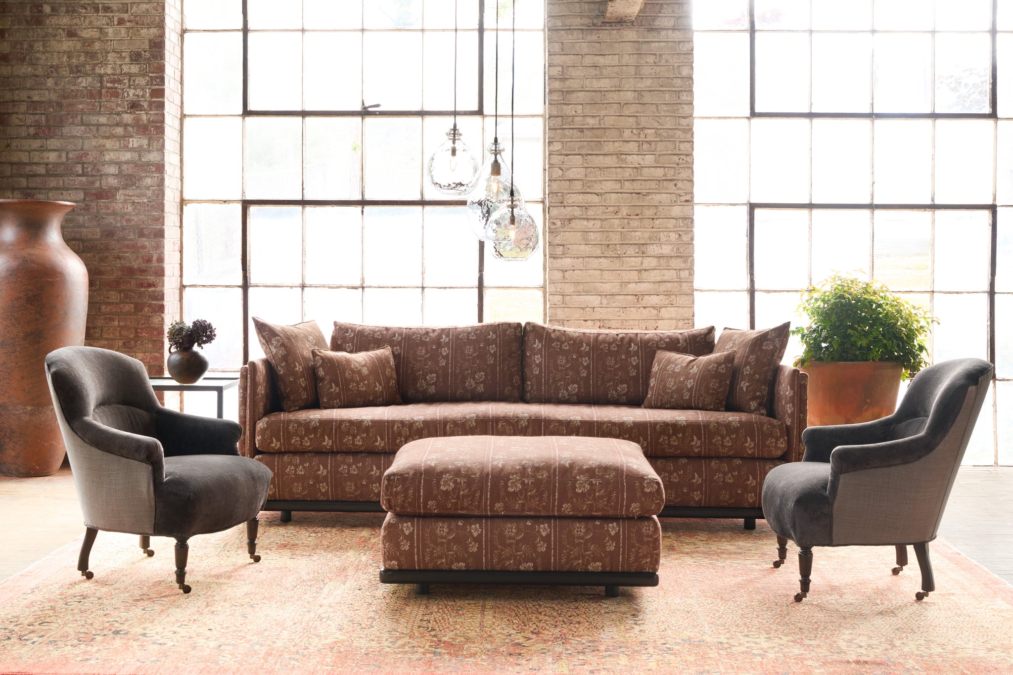  Living room with patterned sofa, chairs, and ottoman in front of large windows. Photographed in Foret Rust. 