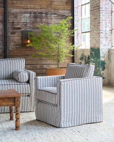 Striped chair next to a striped sofa in front of a wood wall with a planter. Photographed in Bridget Chestnut.