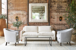  Cream sofa in front of wood wall with two grey leather chairs on each side. Photographed in Lan Birch. 