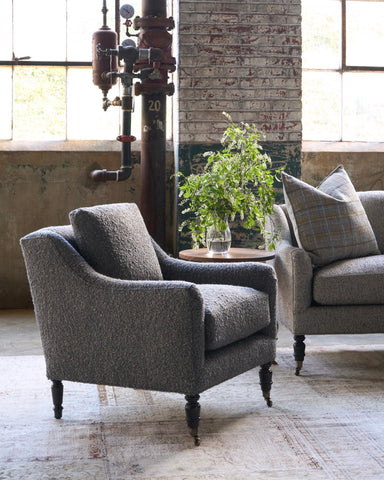 Brown chair in a showroom next to a sofa with a wood table and a bouquet on top. Photographed in Knobby Coffee.