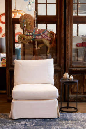  Seda chair in Molino Ivory next to a metal side table. In the background is a wood cabinet with a large decorative carousel horse. Photographed in Molino Ivory. 