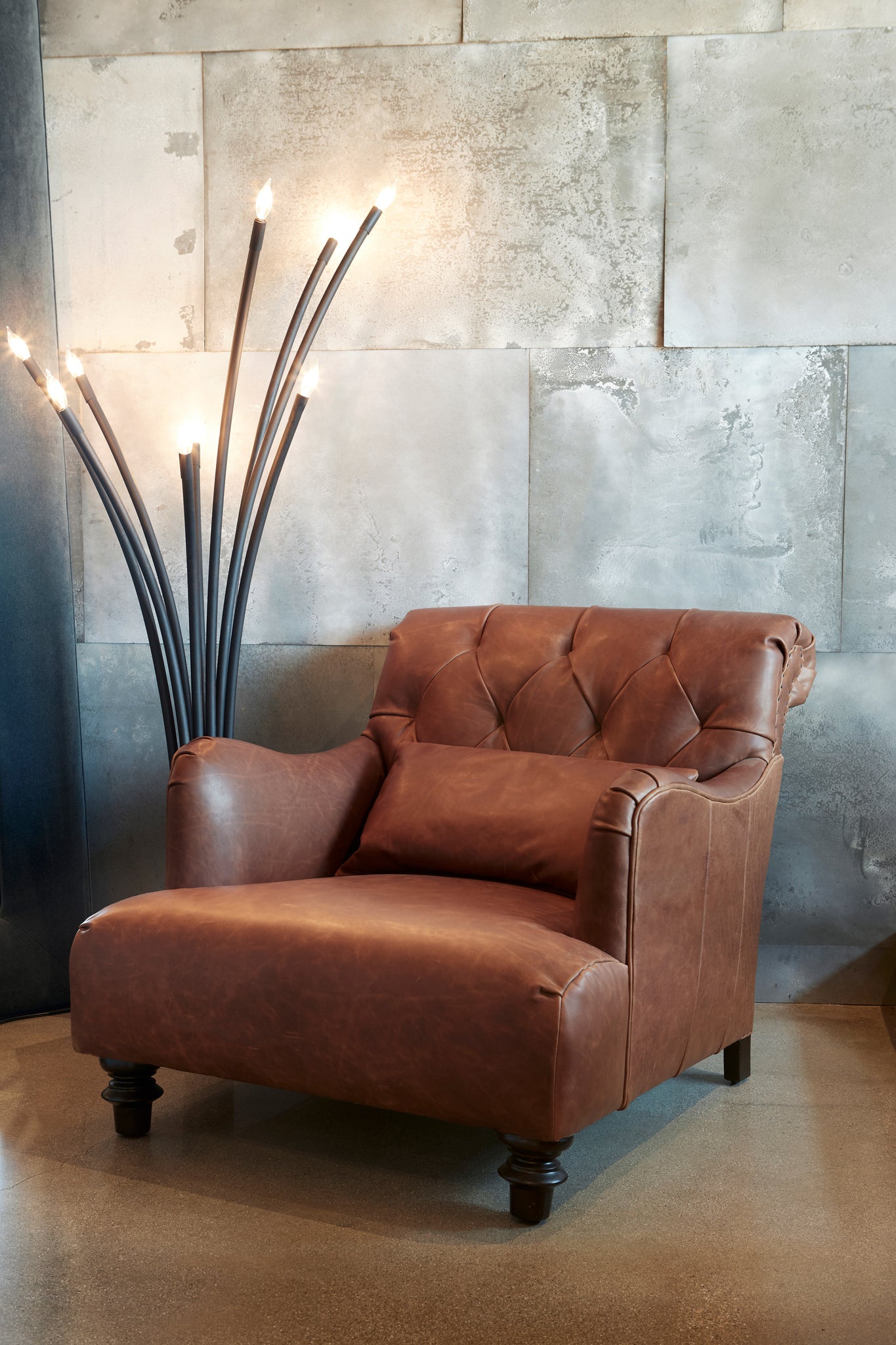  Brown leather chair in front of a metal tile wall. Floor lamp of the left. Photographed in Spur Terracotta. 