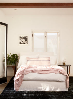  April bed in Logan White next to two side tables. In the background is a white wall room with a large window and a single black and white photo hanging. Photographed in Logan White. 