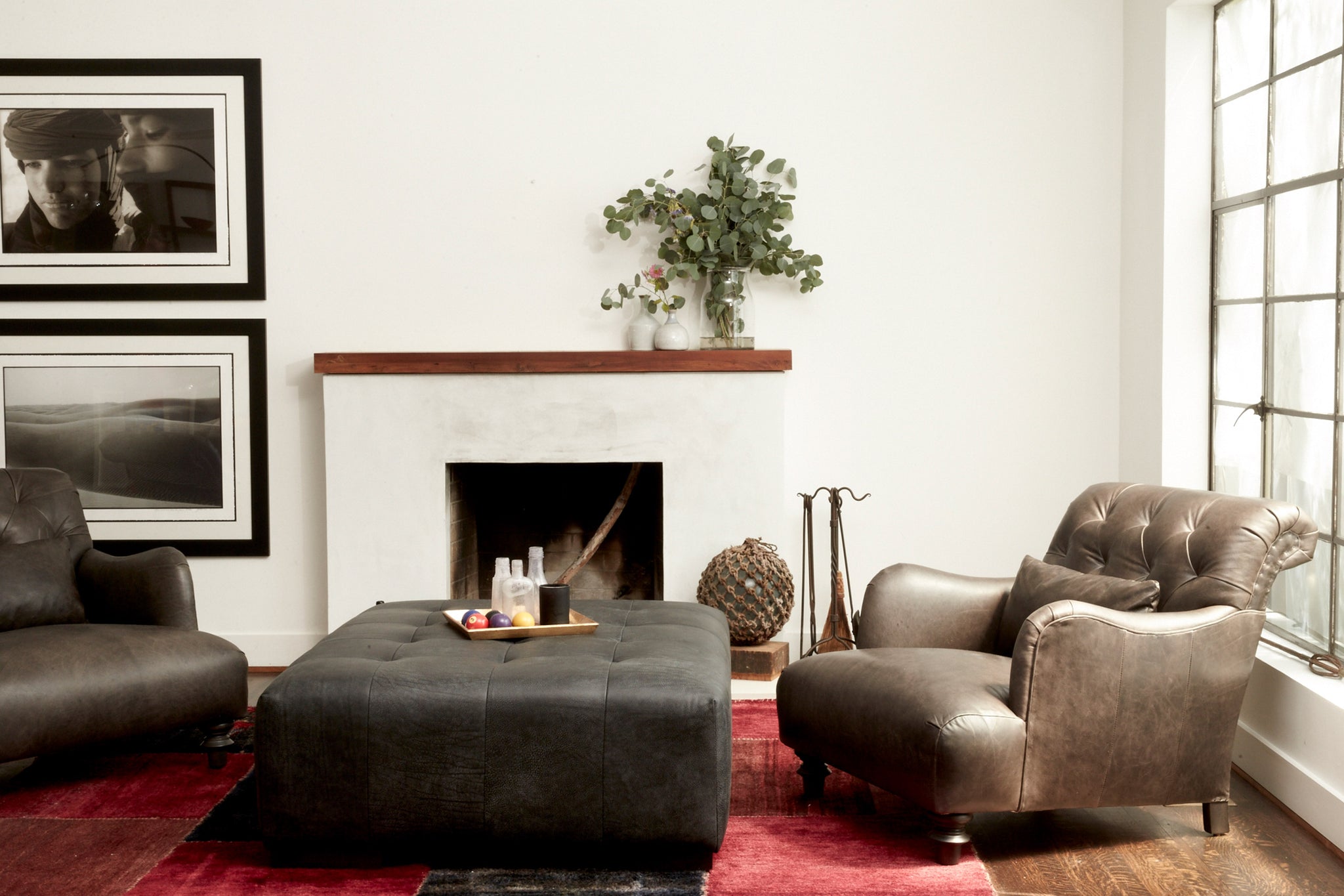  Arden Ottoman in Indiana Charcoal next to two leather chairs. Photographed in Indiana Charcoal. 