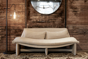  Metal floor lamp with clear circular pendant next to a sofa with neutral fabric sitting in front of a wood wall.  
