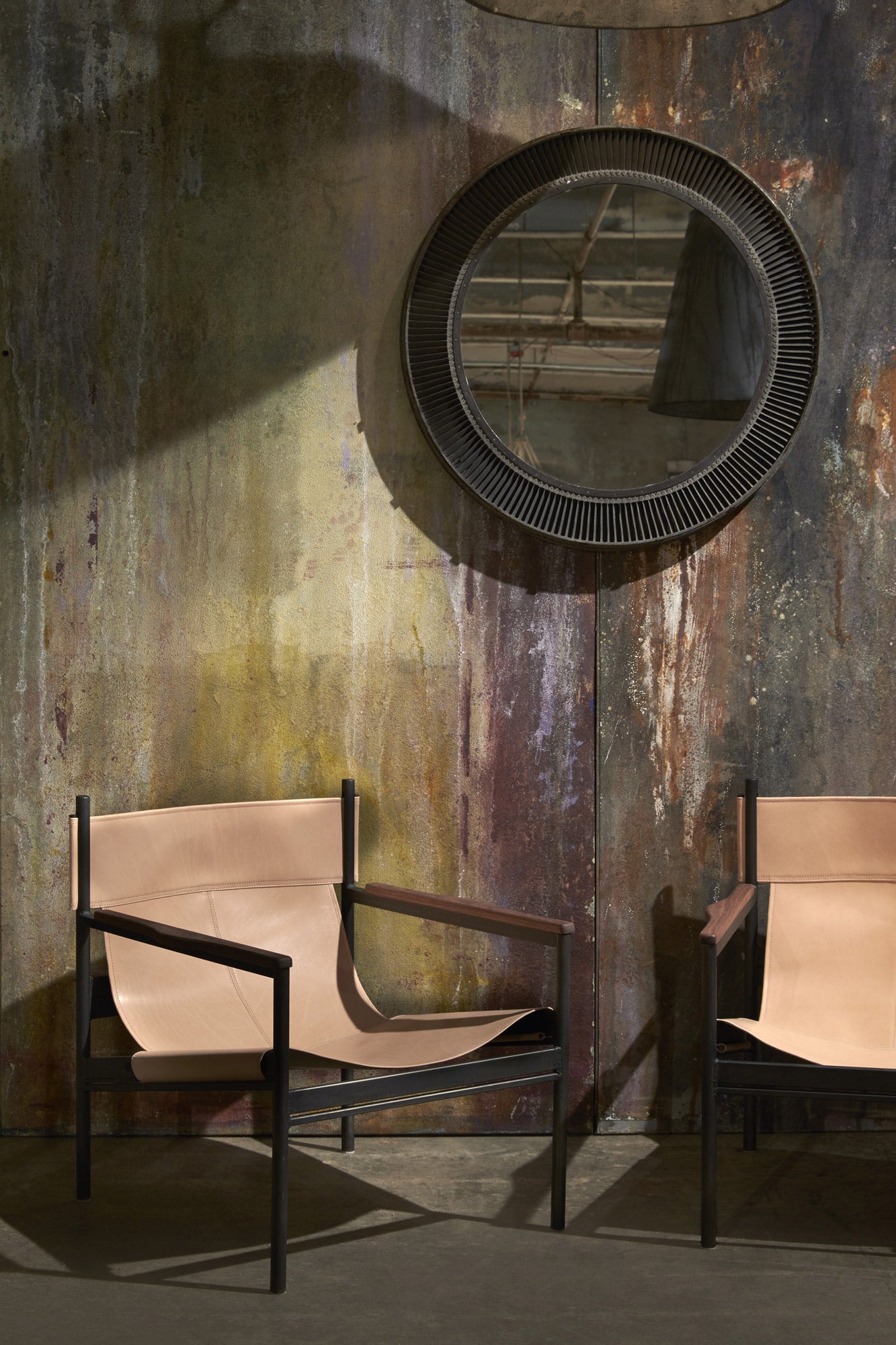  Two chairs in Vachetta Natural. In the background is a concrete wall with a mirror hanging. Photographed in Vachetta Natural. 