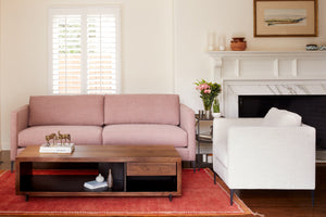  Pink sofa in living room with white chair and wood coffee table. Photographed in Clayton Flax. 