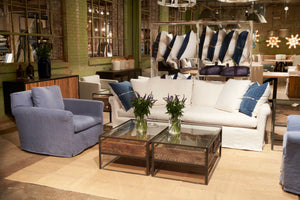  Chair in Logan Federal Blue with a white colored sofa and wood coffee table. In the background is a green wall with large windows and decorative pillow sets.Photographed in Logan Federal Blue. 