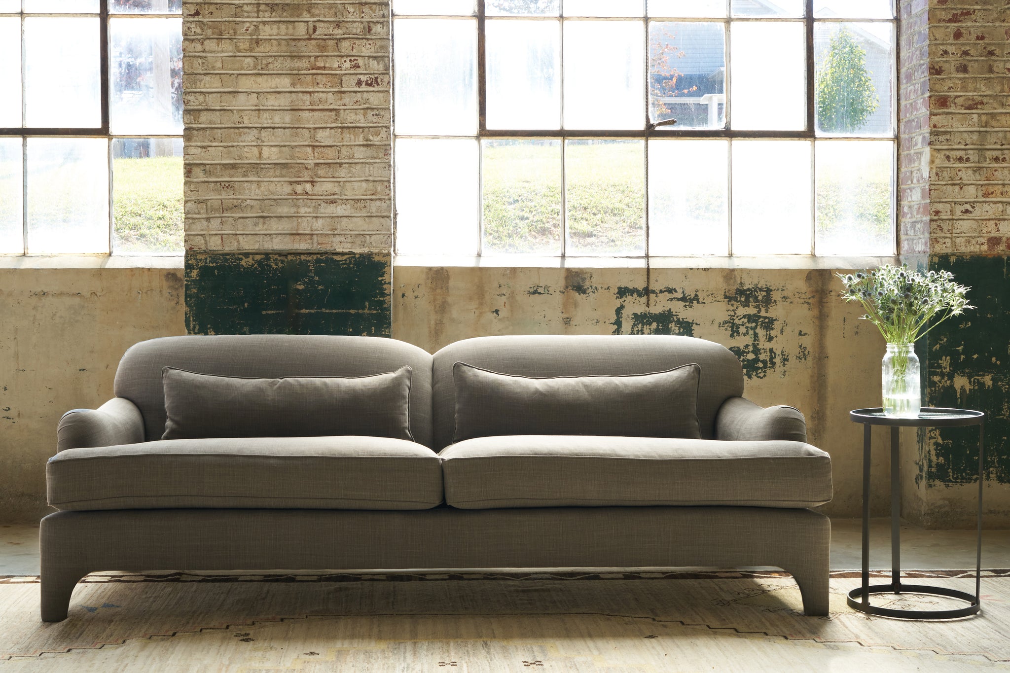  Sofa in front of large windows. Photographed in Rye Warm Grey. 
