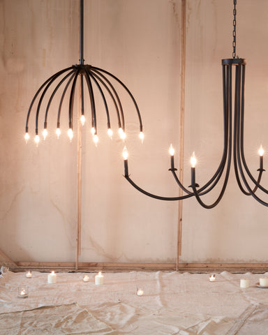 Two chandeliers hanging from ceiling. Curved arms on chandelier and black finish. 
