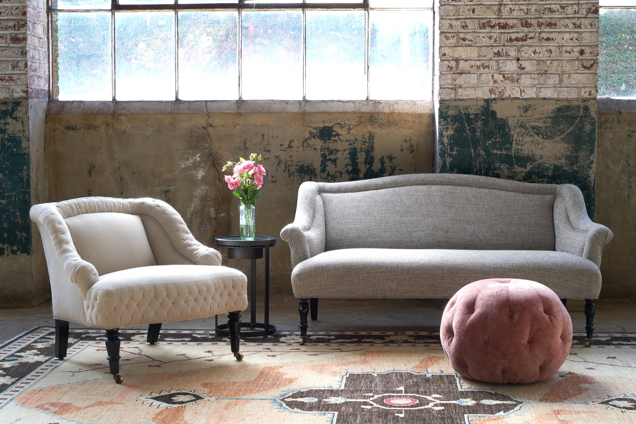  Bog loveseat with a chair on the left and a pink pouf in front. Photographed in Salerno Slate. 
