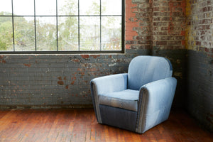  Chair in Recycled Denim. In the background is a brick wall with a large glass window. Photographed in Recycled Denim. 