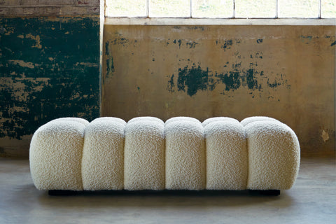 Cole bench in Wooly White in the center of a room with concrete walls in the background.Photographed in Wooly White