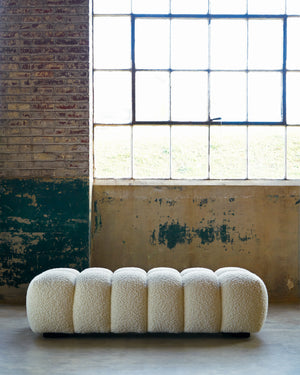  Cole bench in Wooly White in the center of a room with concrete walls in the background.Photographed in Wooly White 