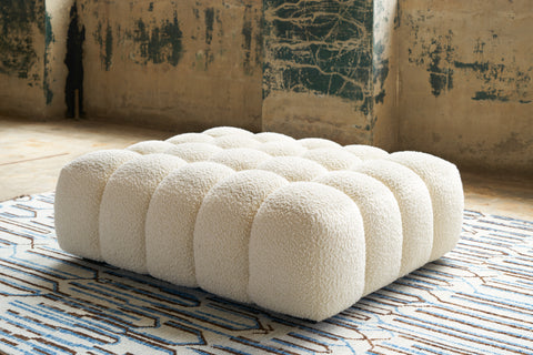 Cole Ottoman in Wooly White. Underneath is a textured tug. Photographed in Wooly White.