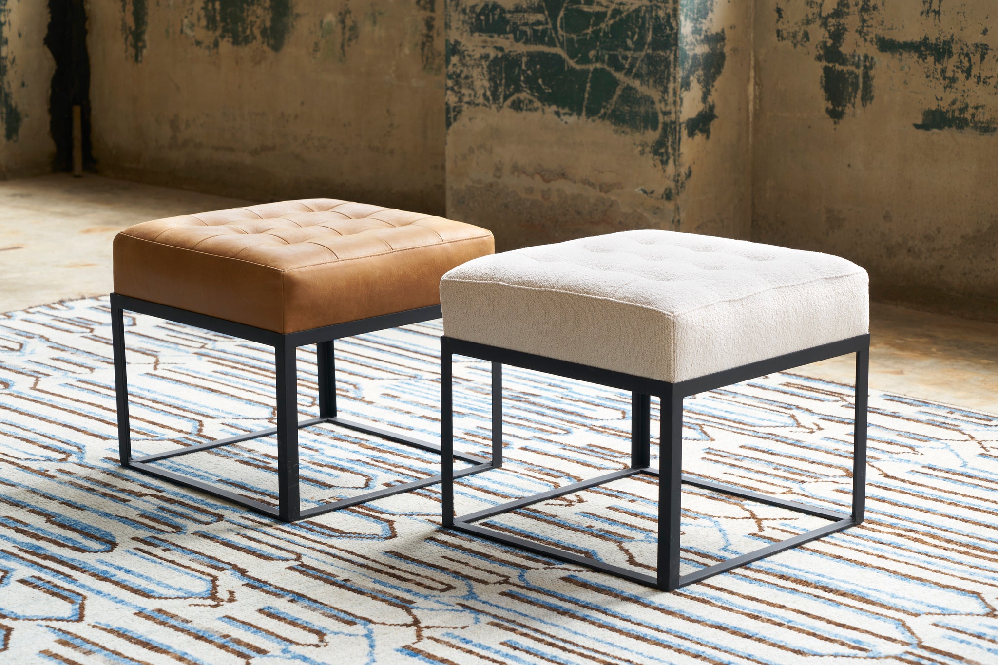  Cruz Ottomans in a showroom on a blue and brown rug. Photographed in Marvell Chestnut and Lumi Bone 