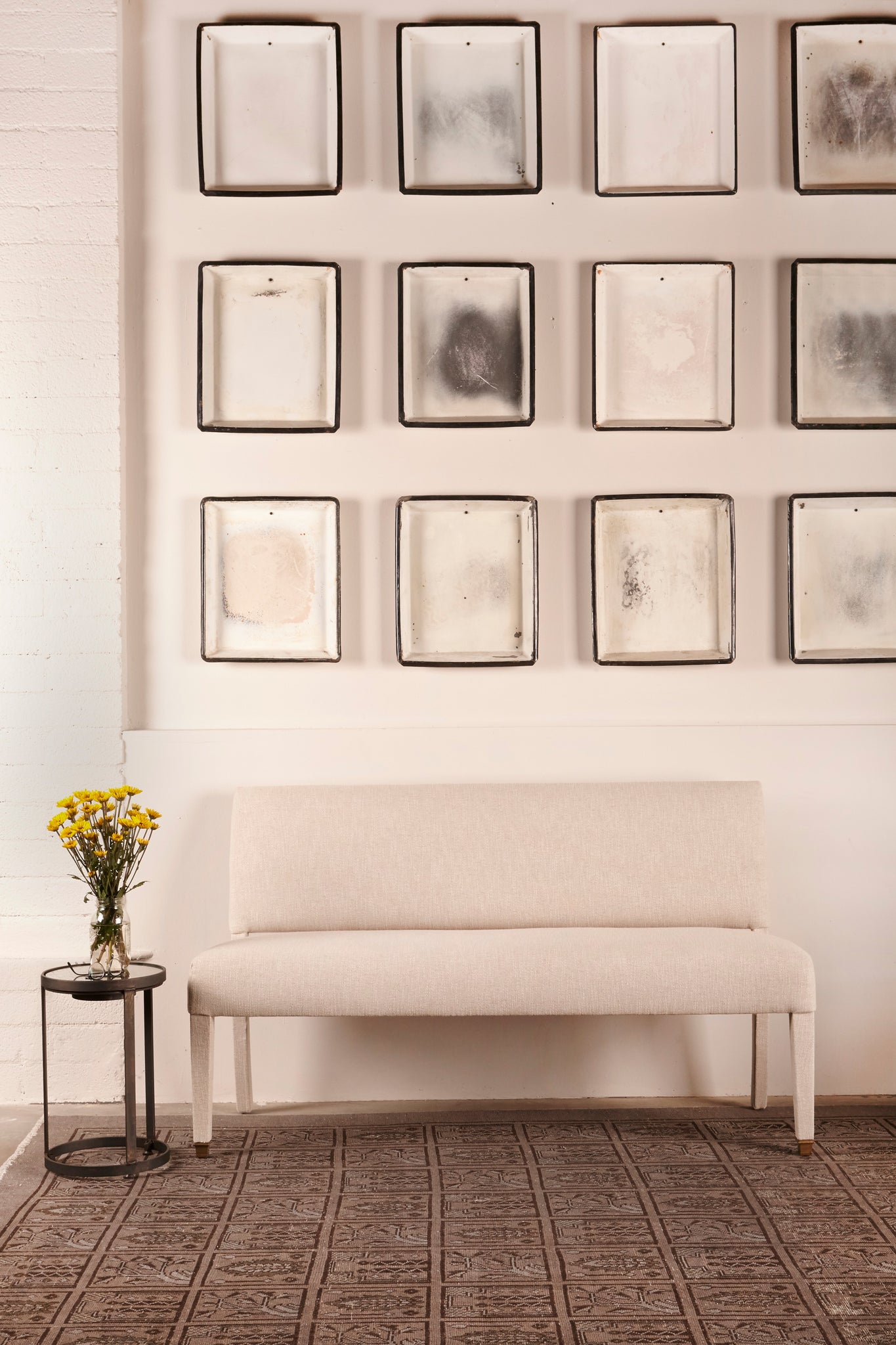  white wall interior with art in grid on wall and one white banquette  