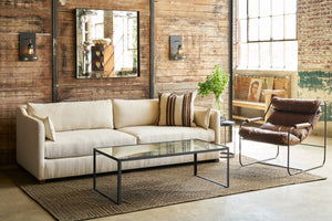  A cream sofa in front of a wood wall with a brown leather sofa on the right. Photographed in Spur Chocolate. 