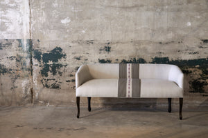  Cream color settee with a large stripe in the middle in front of a vintage concrete wall. Photographed in Oaxacan Runner 