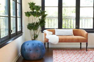 Orange settee in a room with windows and a blue striped pouf on the left. Photographed in Orange Kilim 
