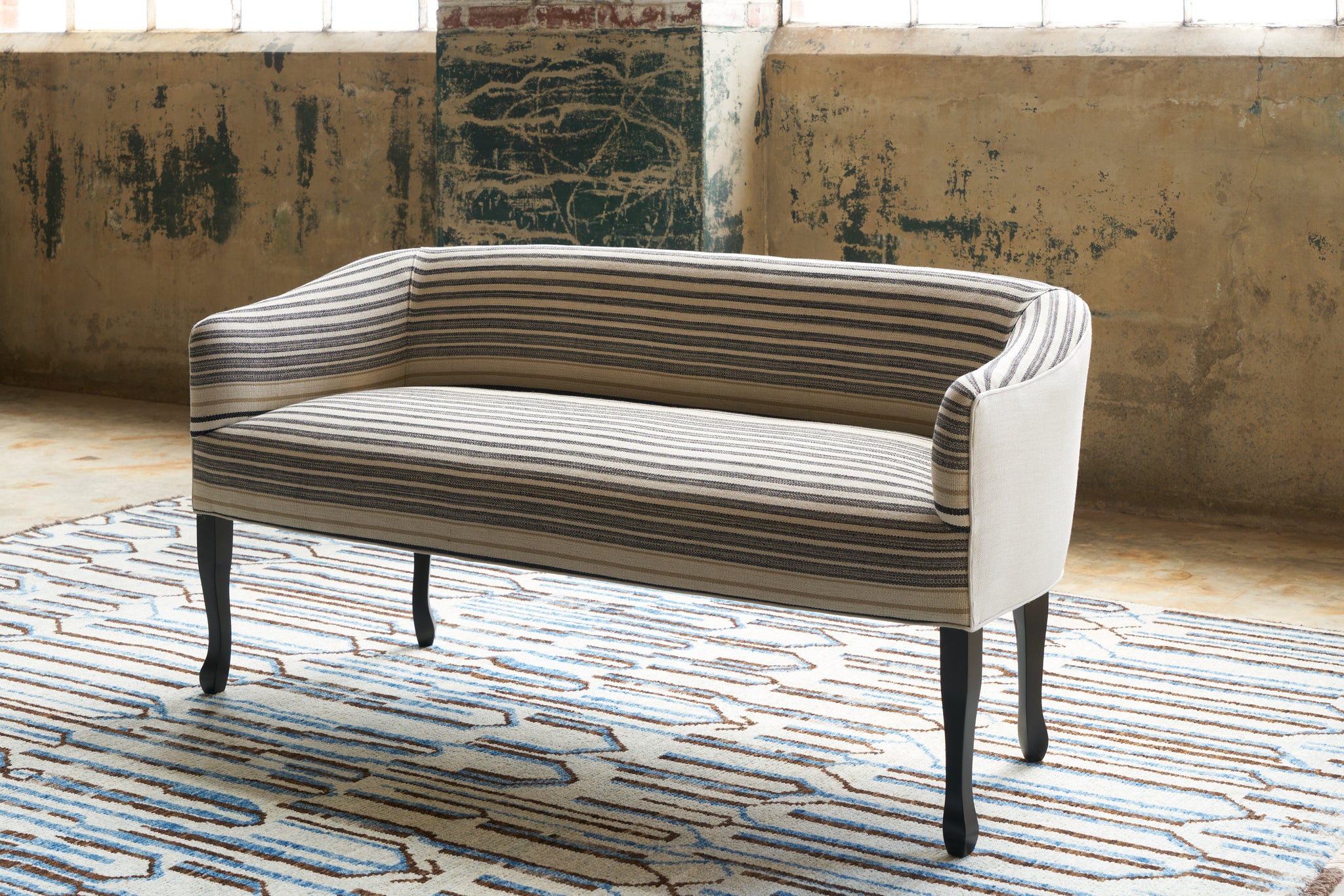  Striped settee on a blue rug with geometric designs. Photographed in Rayas Fino  