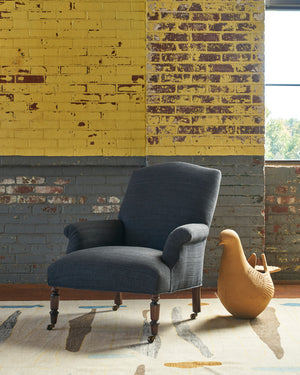  Fritillaria in Rayas Denim in front of an old brick wall painted yellow and grey. There is a clay dove pot on the right side of the chair. Photographed in Rayas Denim. 