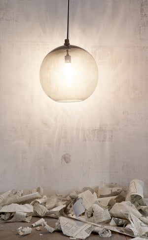  Detailed shot of Globe Pendant in smoke hanging against a white wall and torn newspapers on the floor. 