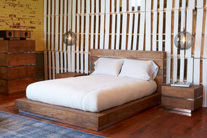  Bedroom with wood platform bed, two wood night stands, wood tall dresser and two globe pendants hanging above each night stand in smoke finish. Bed has white bedding.  