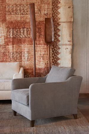  Light brown chair in linen in front of a brown painting. Photographed in Rye Warm Grey. 