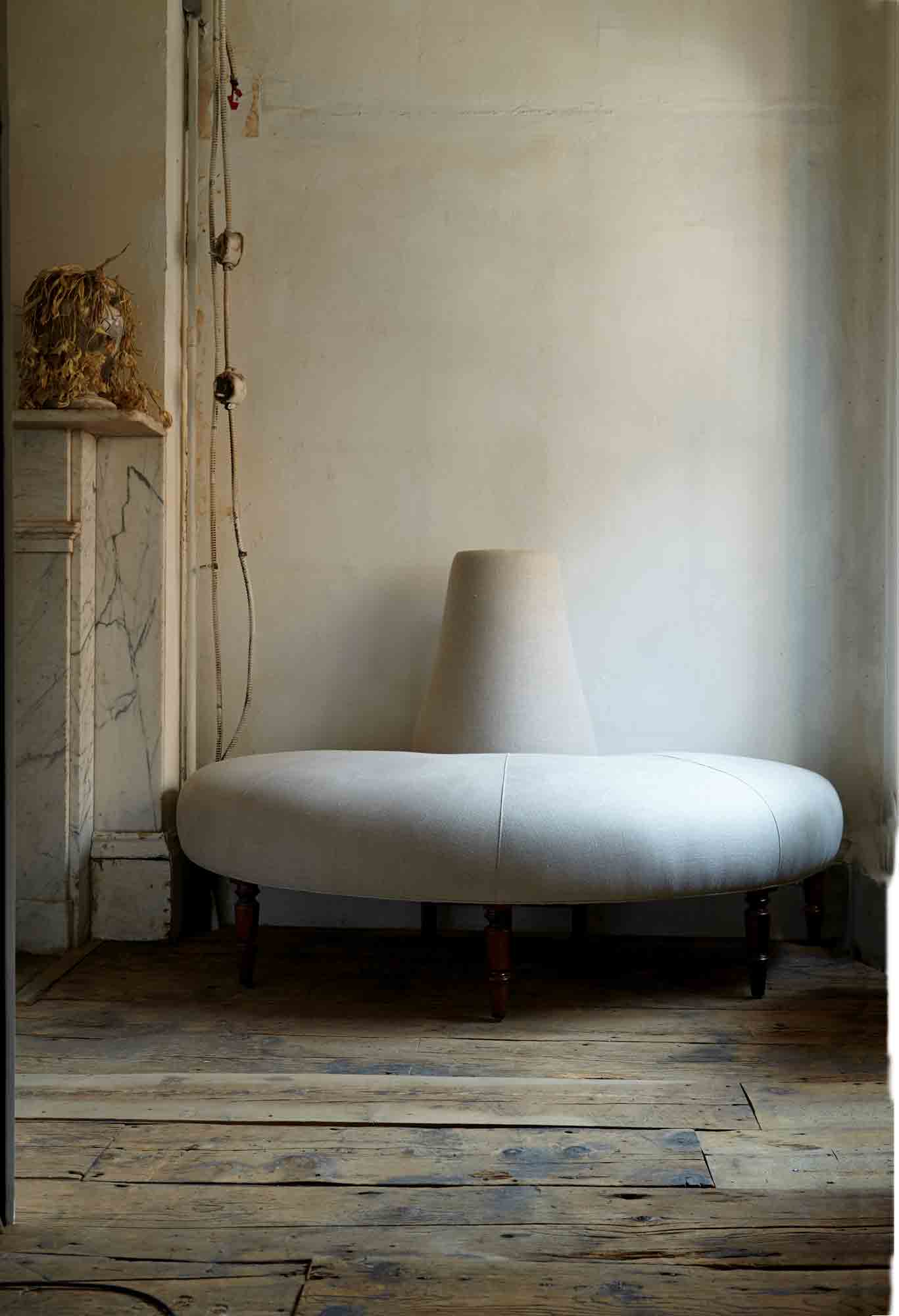  The Half Coin sofa is in Vintage Flax against a wall in a room with soft daylight and a wood floor. Photographed in Vintage Flax. 