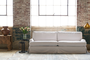  White sofa in front of a large window with pink flowers on the left and an auburn glass light on the right. Photographed in Naomi White. Photographed in Naomi White 