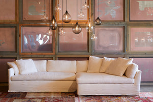  Harbor Sectional in Molino Ivory. Underneath the sectional is a red patterned rug. Above the sectional hangs multiple jug lamps. Photographed in Molino Ivory. 