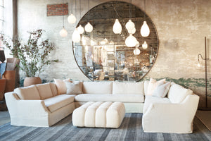  Three piece sectional in front of a large round mirror with white glass pendants and a white ottoman in the middle. Photographed in Brevard Birch. 
