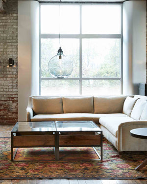  Upholstered sectional with neutral fabric and coffee table placed in front with metal glass top and metal base with jug lamp extra large lamp in smoke finish.  