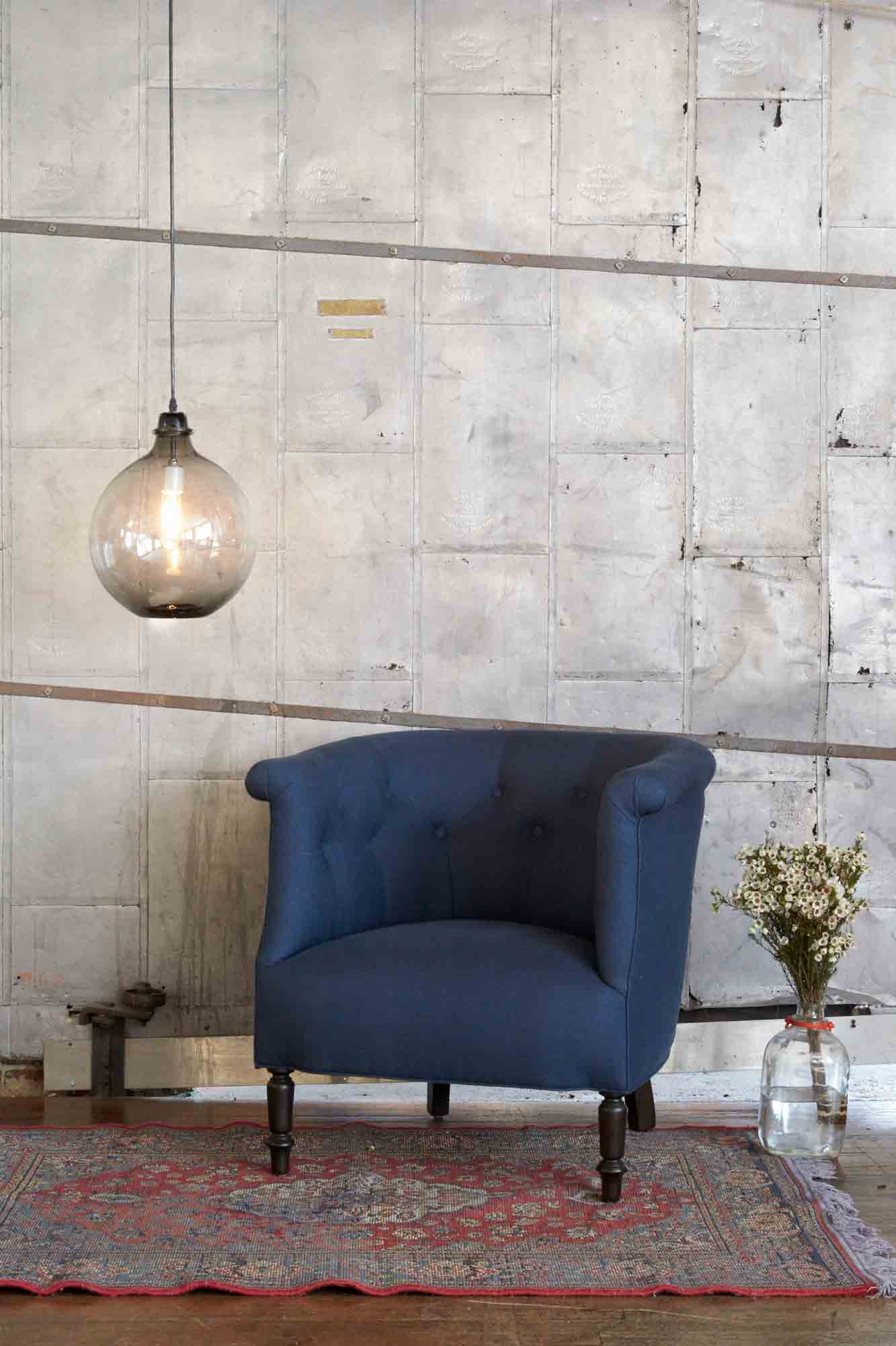  Upholstered chair in blue fabric with extra large jug lamp hanging next to it in smoke finish.  