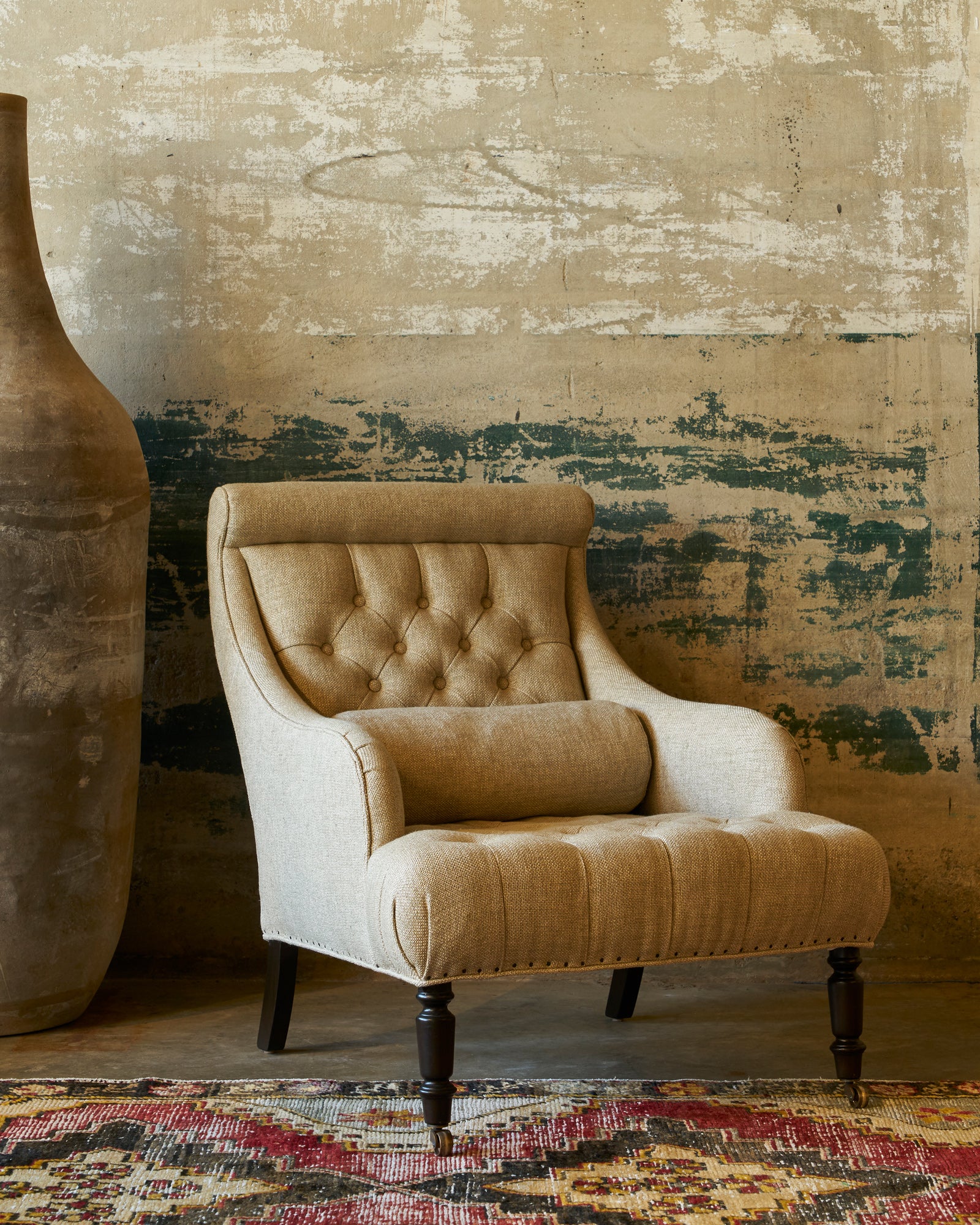  The Juliet chair is angled in front of a concrete wall and next to a large clay pot. Photographed in Avery Oatmeal 