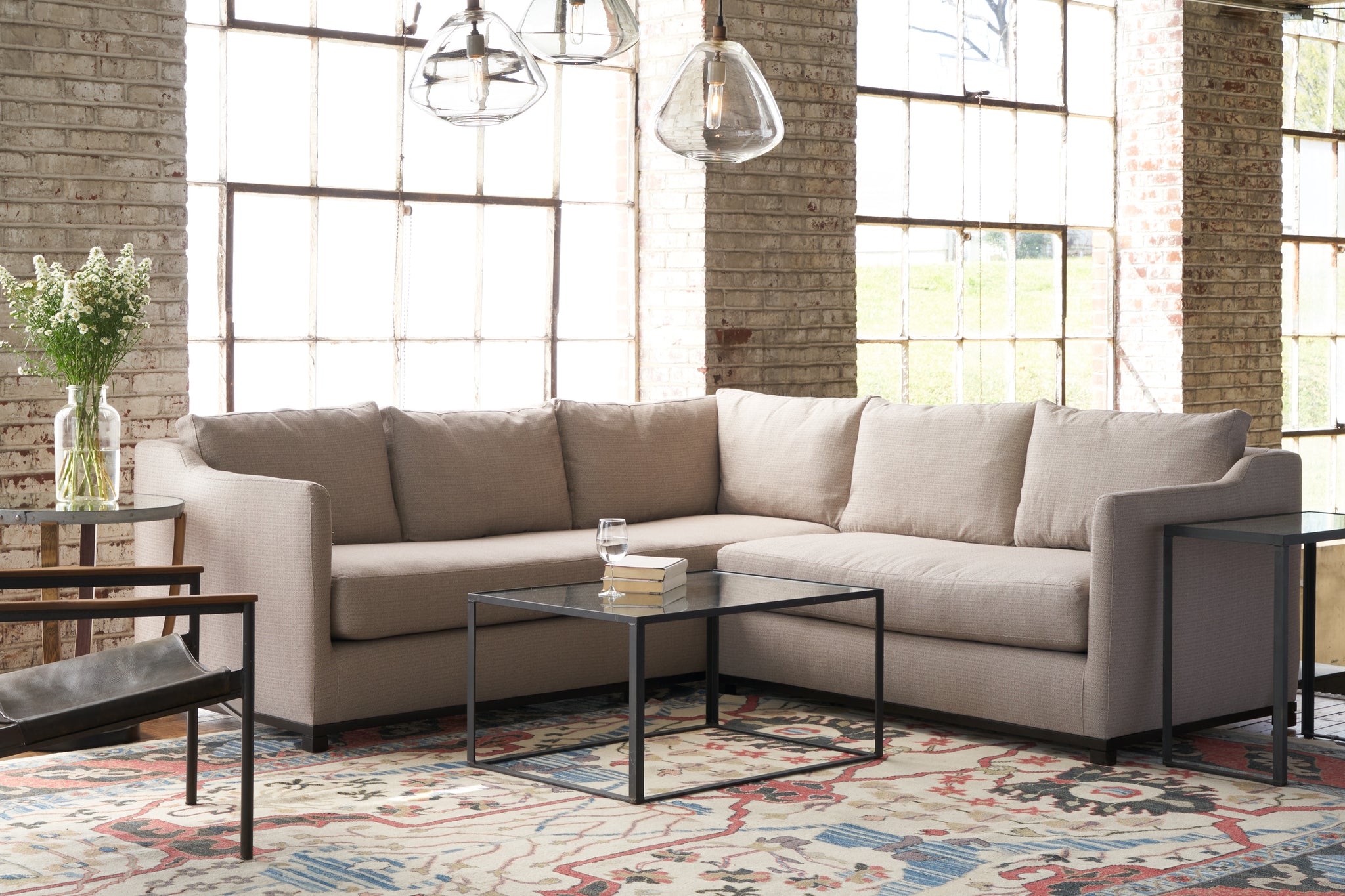  Kardell Sectional in Carta Hazelnut next to a glass coffee table with lamps hanging above.Photographed in Carta Hazelnut. 
