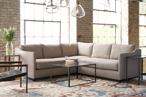 Kardell Sectional in Carta Hazelnut next to a glass coffee table with lamps hanging above.Photographed in Carta Hazelnut.