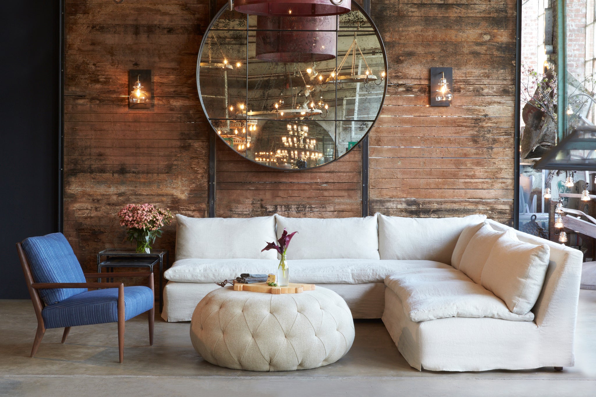  Montauk chair in Bengal Pin Stripe Indigo next to a light sofa and ottoman. In the background is wood wall with a mirror and lamps hanging from it. Photographed in Bengal Pin Stripe Indigo. 