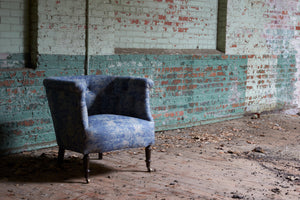  Madeline chair in Mariko Indigo. In the background is a brick wall. Photographed in Mariko Indigo. 