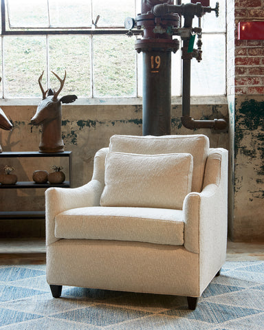 Milo chair in Seguro Natural next to a black table with a decorative deer haed. In the background is a brick wall with a large industrial pipe. Photographed in Segura Natural.