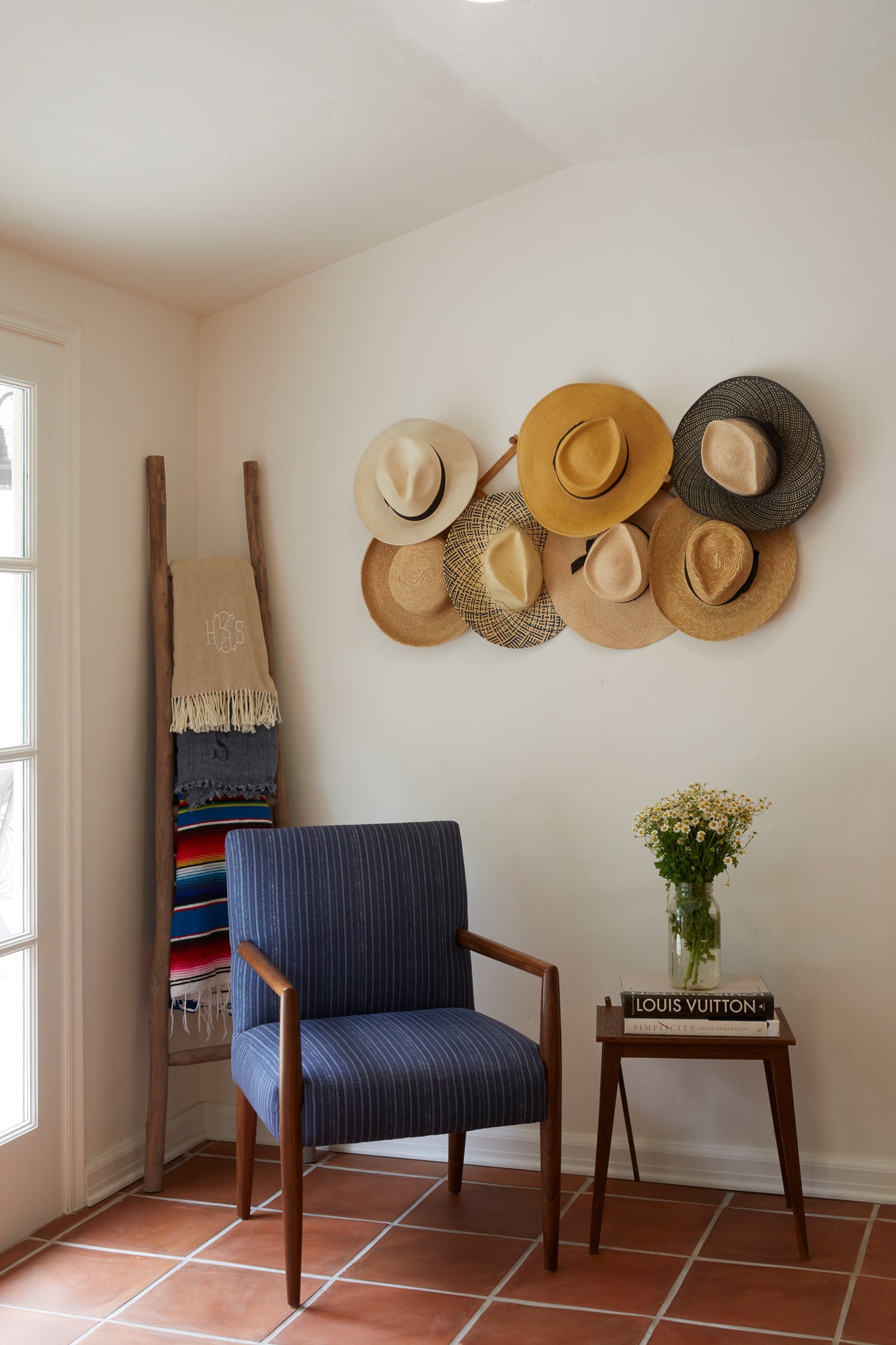  Montauk chair in Bengal Pin Stripe Indigo next to a wood table. In the background is a light room with colorful blankets and hats hanging. Photographed in Bengal Pin Stripe Indigo. 