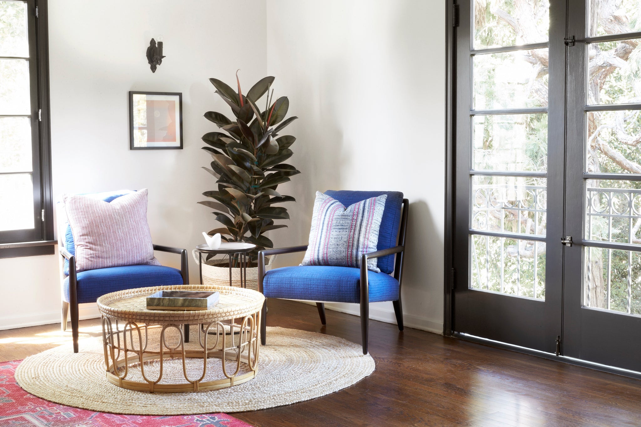  Montauk chair in Blue Alta Dena next to a coffee table and potted plant. In the background is a white room with a dark door. Photographed in Blue Alta Dena. 