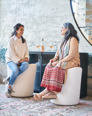  Two counter stools in white in front of a dark credenza. Two people are sitting on the stools. Photographed in Lumi Bone 