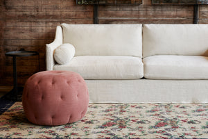  Pouf 26 Ottoman in Rye Terra next to a light sofa. Photographed in Rye terra. 