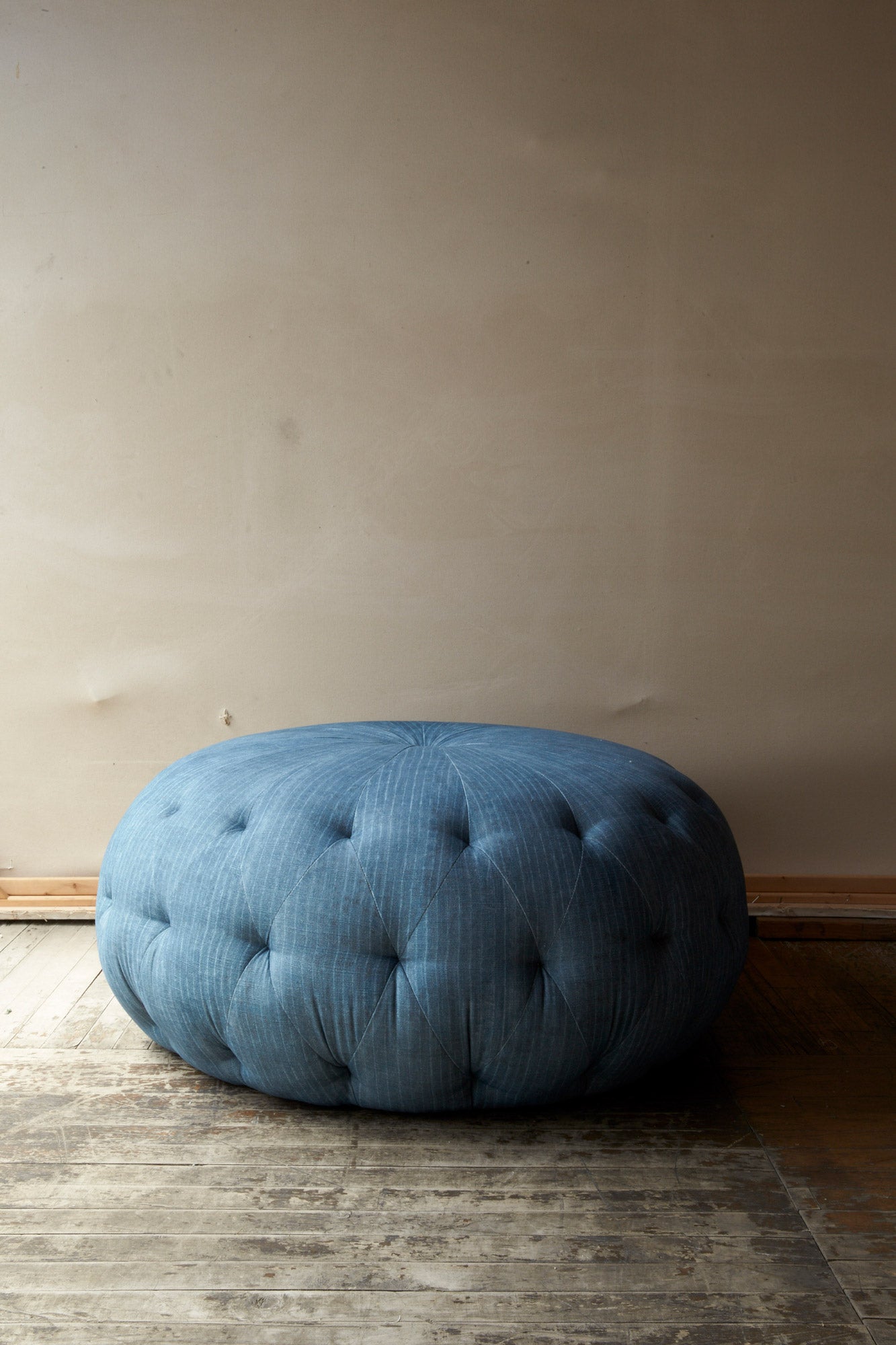  Pouf Ottoman 36 in Levi Indigo (discontinued) in an empty room. Photographed in Levi Indigo. 