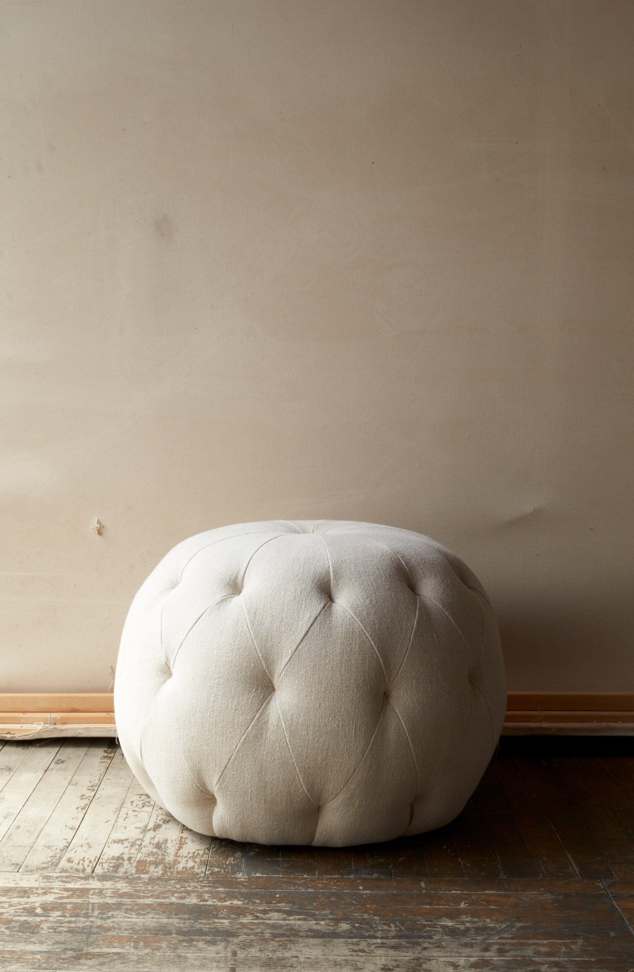  Pouf Ottoman in Brevard Natural in an empty room. Photographed in Brevard Natural. 