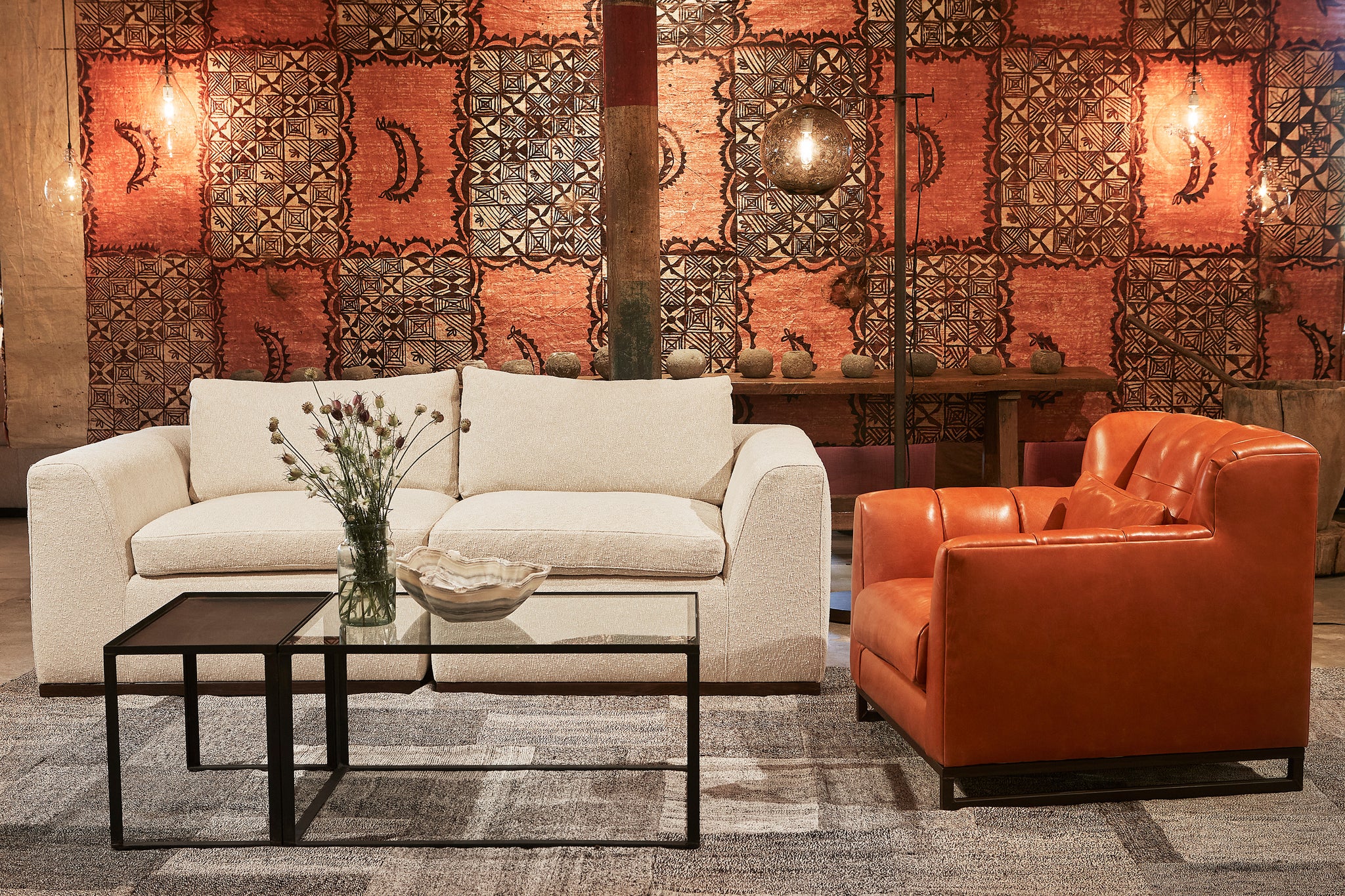  Richard chair in Dawson Rust next to a light sofa and a glass coffee table. In the background is a patterned red wall. There is also a floor lamp behind the sofa. Photographed in Dawson Rust. 